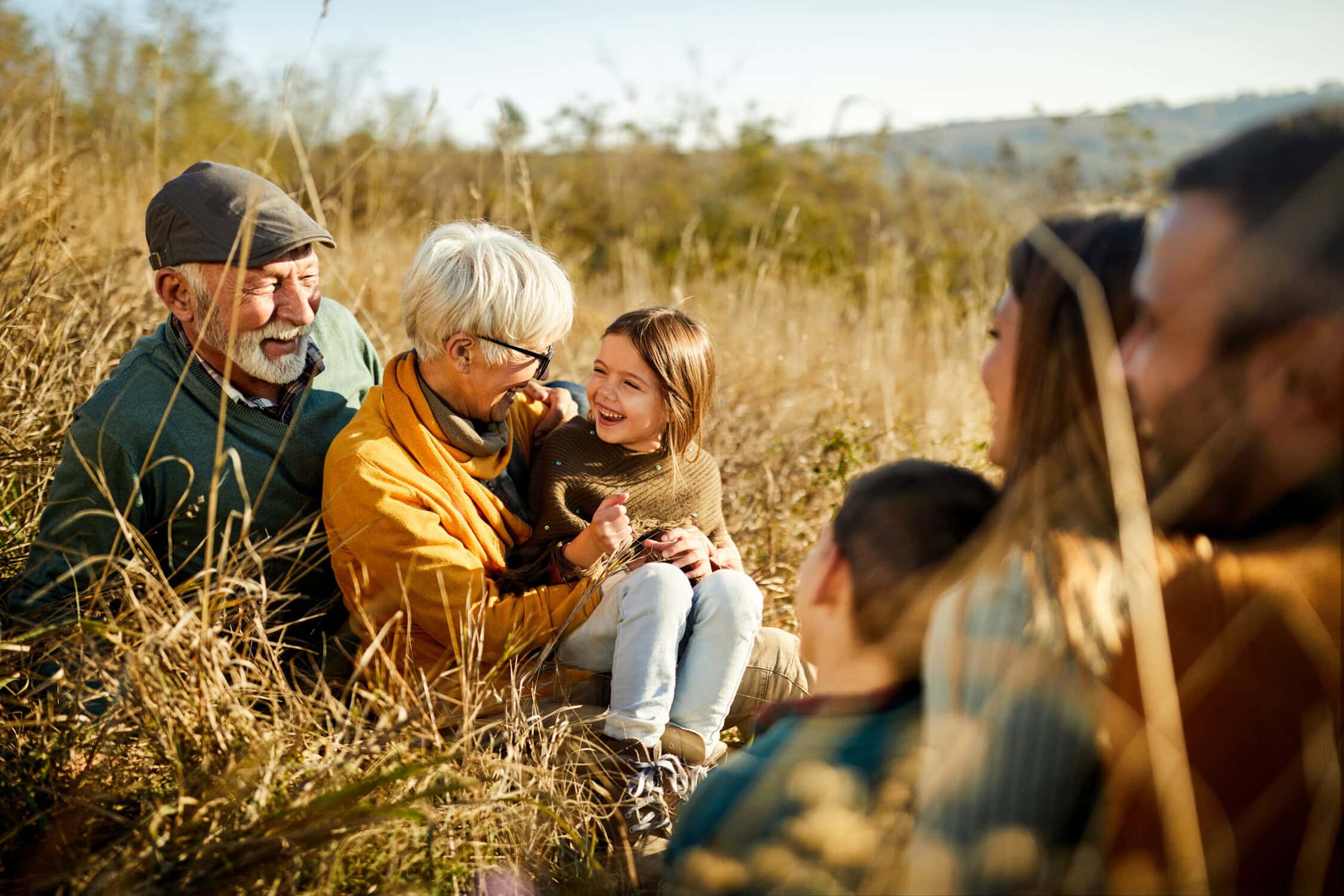 Gezinnen genieten van een leuke dag in de natuur bij de Vliegbasis, met zonnig weer en gouden grasvelden, perfect voor familie-uitjes en outdoor activiteiten.