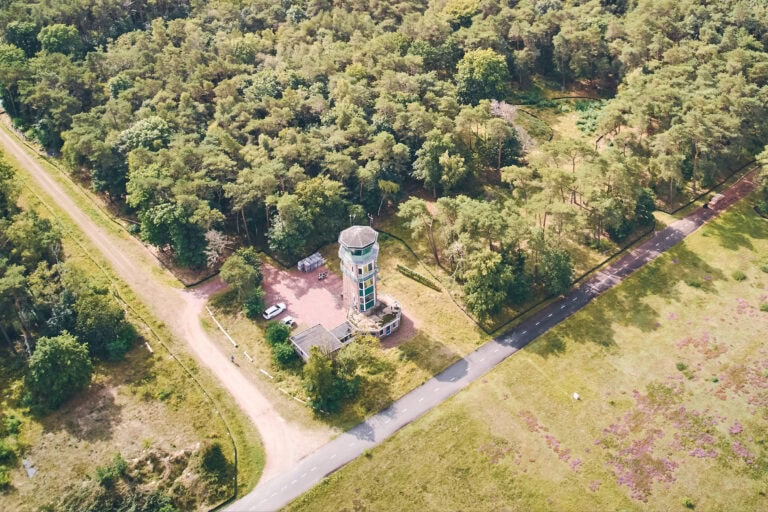 Vliegbasis Nederland met controle tower en omringende groene natuurpaden, ideaal voor militaire en burgerluchtvaart, gelegen in een bosrijke omgeving voor strategisch vliegverkeer.