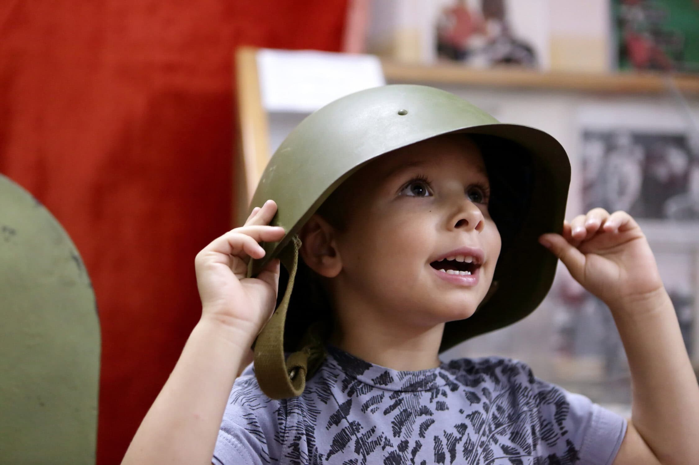Kinder krijgt militaire helm op tijdens educatief bezoek aan de vliegbasis.