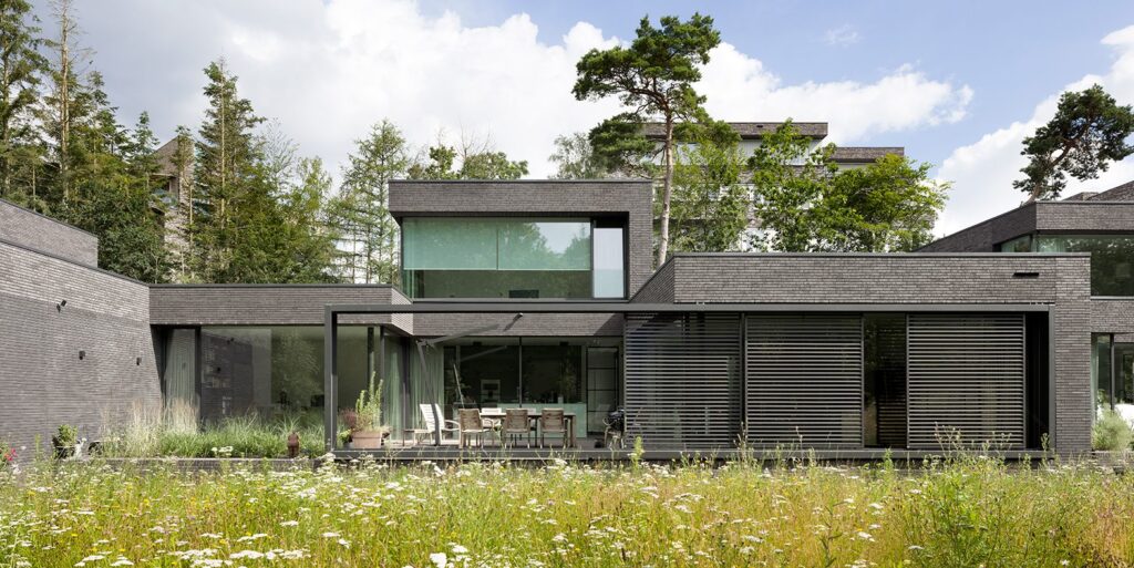 Elegant modern woning met strakke architectuur, natuurlijke materialen en grote raampartijen, gelegen in een bosrijke omgeving bij de Vliegbasis. Het ontwerp combineert functionaliteit met esthetiek en past perfect in de natuurlijke omgeving.