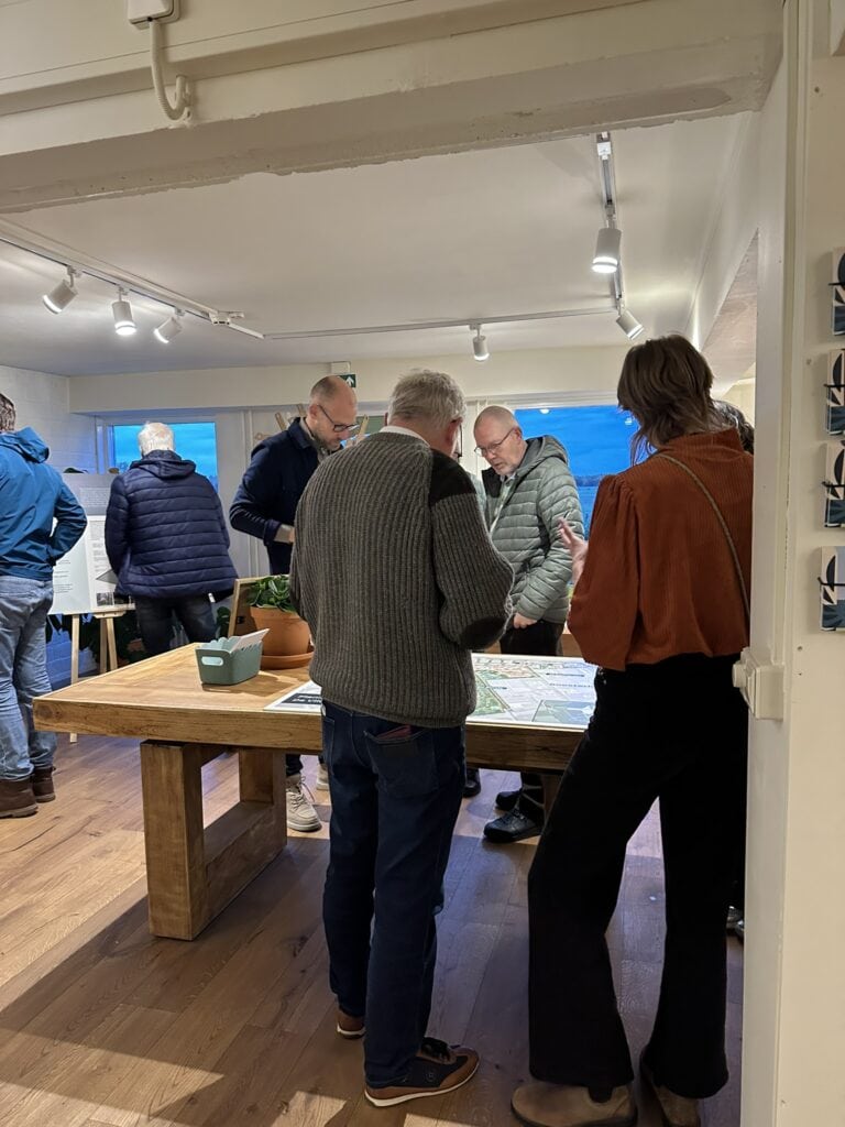 Moderne museale tentoonstelling over de Vliegbasis met bezoekers die informatie bekijken en genieten van de historische displays.