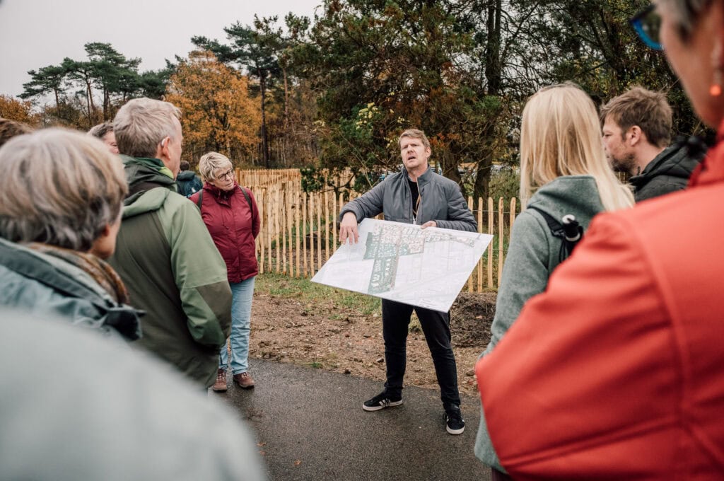 Uitleg over de plannen voor de herontwikkeling van de Vliegbasis aan een groep geïnteresseerden.
