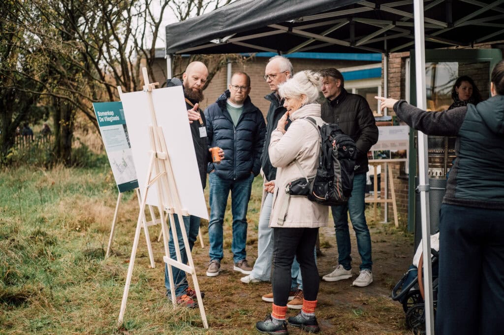 Duidelijke uitleg over de Vliegbasis tijdens een informele buitenpresentatie met bezoekers en gidsen.