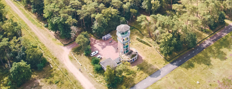 Uitkijktoren op een vliegveld gelegen in een bosrijke omgeving, ideaal voor natuur- en vliegveldbezoekers, met parkeerplaatsen en wandelroutes rondom, schitterend uitzicht over de groene omgeving.
