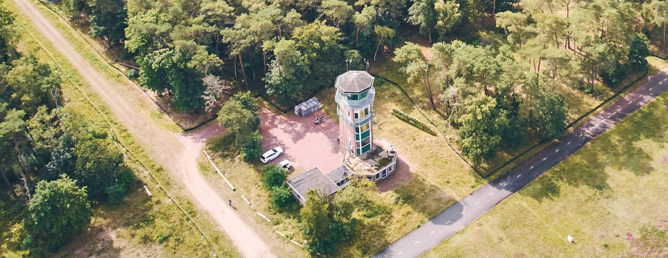 Uitkijktoren op een vliegveld gelegen in een bosrijke omgeving, ideaal voor natuur- en vliegveldbezoekers, met parkeerplaatsen en wandelroutes rondom, schitterend uitzicht over de groene omgeving.