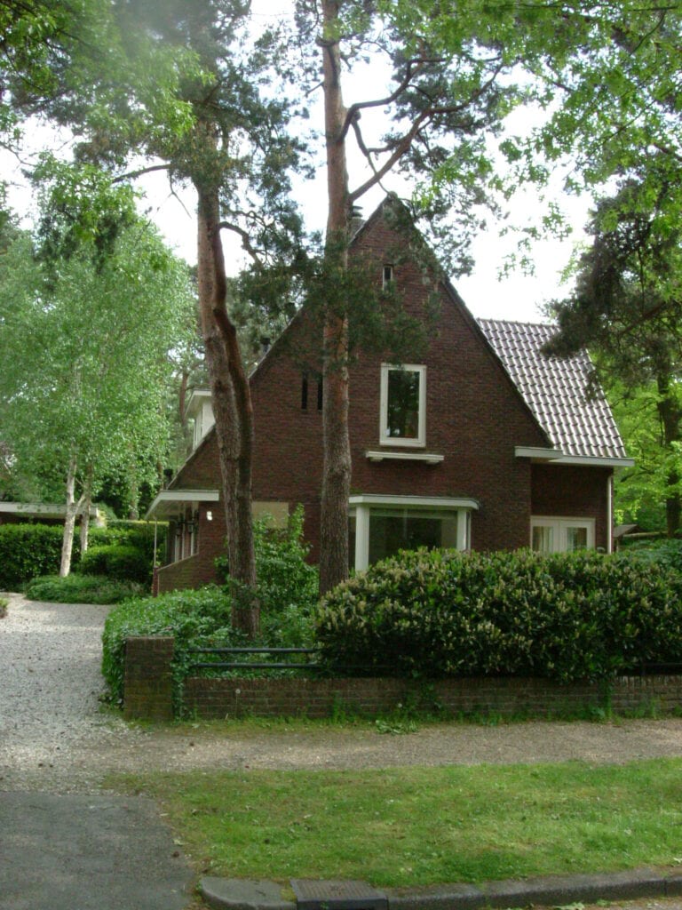 Traditioneel huis in bosrijke omgeving met groene bomen en tuin, gelegen op de Vliegbasis.