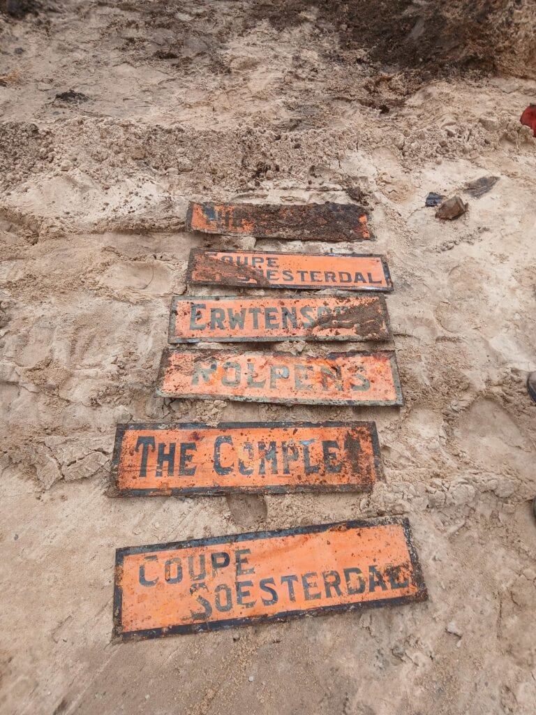 Een close-up van oude, verweerde herinneringsborden in de grond, met inscripties zoals 